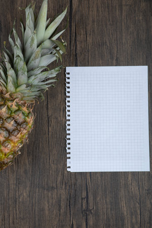 Photo of ripe juicy pineapple and empty paper on black surfaceの写真素材