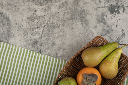 Delicious fuyu persimmon and ripe pears in wicker basketの写真素材