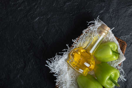 Fresh healthy oil with organic green peppers over black background