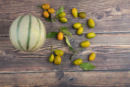 White melon and fresh kumquat fruits on wooden surfaceの写真素材