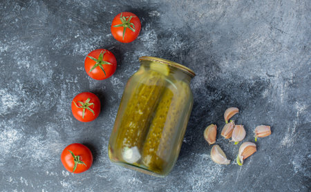 Top view of Fresh tomatoes , pickle jar and fresh garlic on grey background