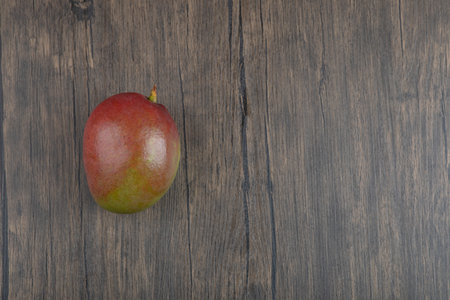 Photo of single fresh mango placed on wooden surfaceの写真素材