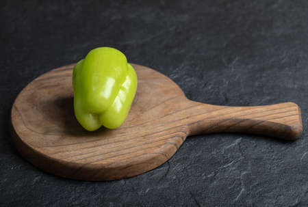 Close up photo of green pepper on wooden board over black backgroundの写真素材