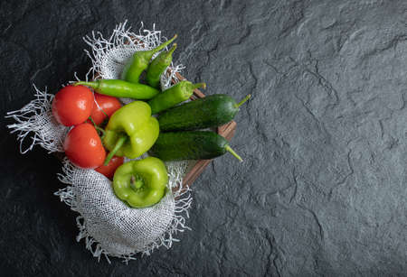 Top view of Pile of fresh vegetables in wooden basket over black background