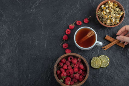 Female hand holding cinnamon on black backgroundの写真素材