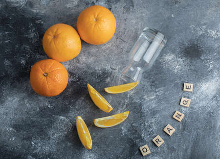 Whole and sliced oranges with empty glassの写真素材