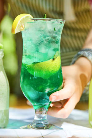 Hand holding a lemonade on wooden table