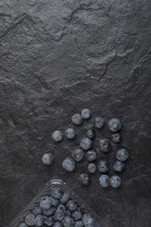 Plastic package of delicious fresh blueberries on black surfaceの写真素材