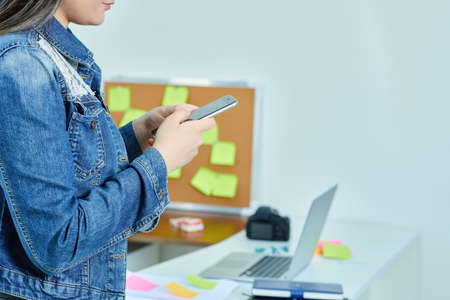 Young beautiful woman writing text with her telephone in the office