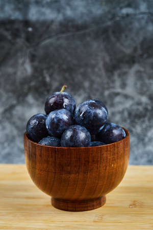 Garden plums in a bowl on wooden tableの写真素材