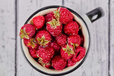 Fresh red raspberries in mug on wooden tableの写真素材