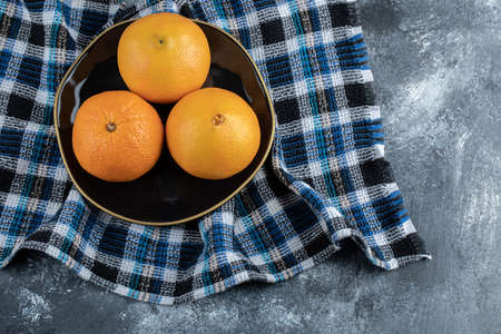 Three ripe oranges on black plateの写真素材