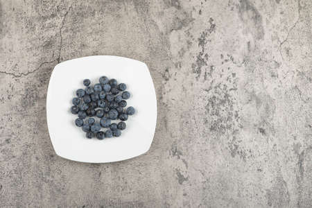 White plate of delicious fresh blueberries on marble surfaceの写真素材