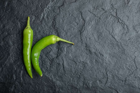 Top view of fresh hot peppers on black background. Horizontal photoの写真素材
