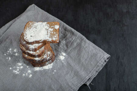 Slices of brown bread with flour on a gray tablecloth