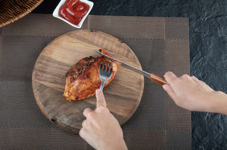 Hands cutting a some chicken on a wooden boardの写真素材