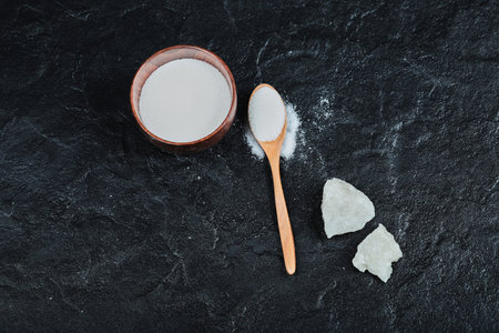 Bowl of sugar with wooden spoon on dark tableの写真素材