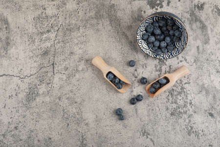 Ceramic bowl of delicious fresh blueberries on marble surface