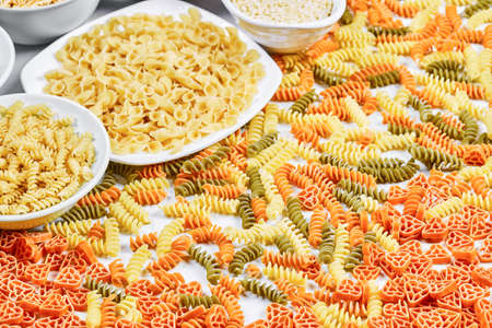 Colorful fusilli and bowls of raw pastas on white backgroundの写真素材