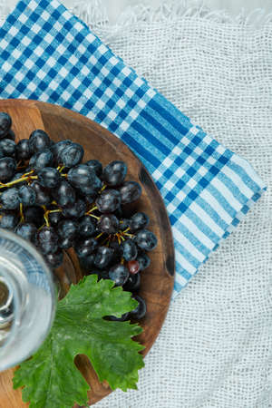 Top view of a cluster of black grapes with leaf and a glass of wineの写真素材