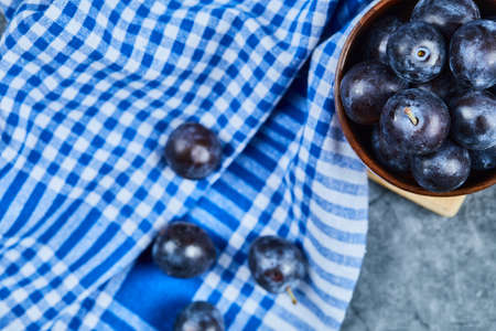 Garden plums in a bowl on a marble background with tableclothの写真素材