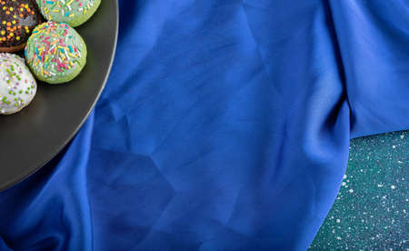 Plate of colorful cookies with sprinkles on blue clothの写真素材