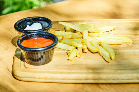 French fries with ketchup and mayonnaise on wooden plate