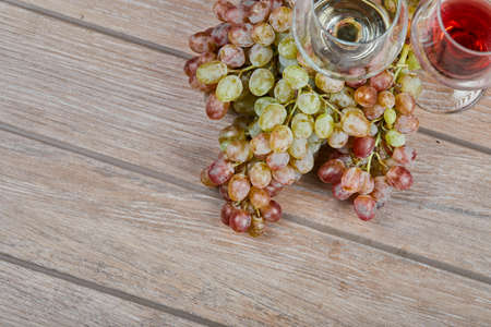 A bunch of grapes and wine glasses on wooden backgroundの写真素材