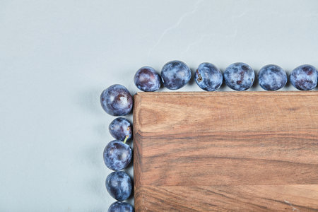 Group of fresh plums around the wooden board