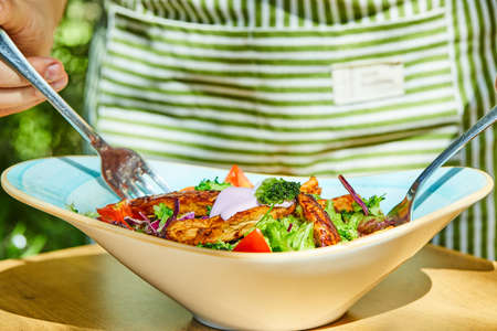 Man taking salad with forks from wooden tableの写真素材