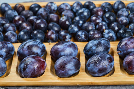 Garden plums on wooden platter, close upの写真素材