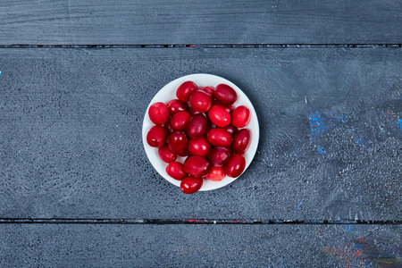 A bowl of red cornel berries on blue backgroundの写真素材
