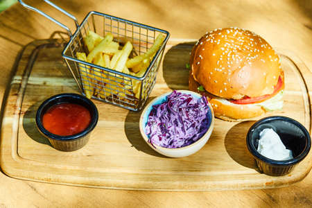 Fresh delicious burger with french fries and sauce on wooden tableの写真素材