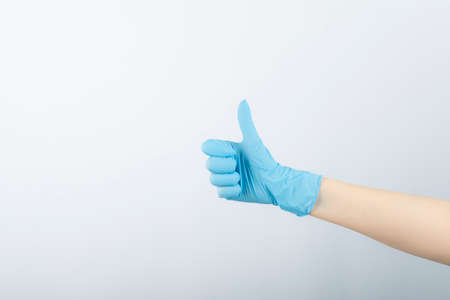 Hand of surgeon in blue medical glove showing a thumb upの写真素材