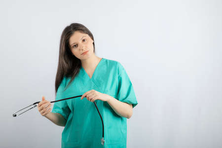 Young nurse playing with stethoscope and looking at cameraの写真素材