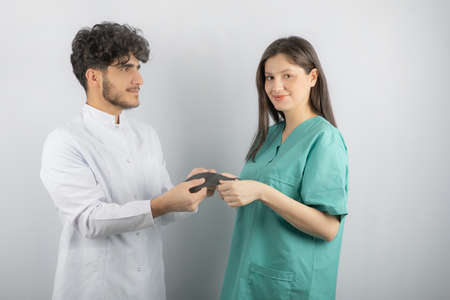 Young happy medical workers. Doc giving nurse her maskの写真素材