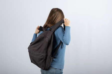Portrait photo of a young girl model standing with backpack and posing