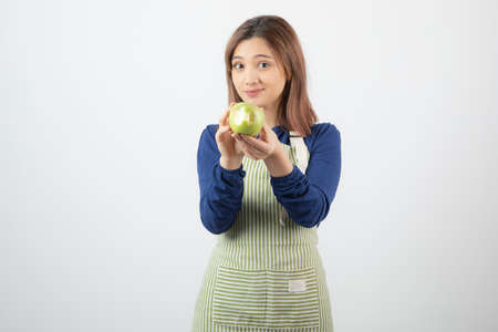 Photo of a cute young woman model in apron holding a green fresh appleの写真素材