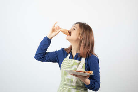 Portrait of young pretty girl eating pizza on white backgroundの写真素材