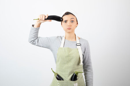 Young housewife showing single eggplant on white backgroundの写真素材