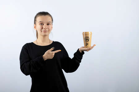 Picture of a young girl model pointing at a cup of coffeeの写真素材