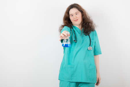 Image of a young girl in green uniform holding a glass jar with blue liquidの写真素材
