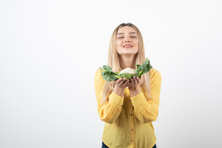 Picture of a smiling pretty woman model standing and holding cauliflowerの写真素材