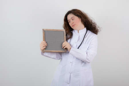 Picture of a young girl model in white uniform holding a frameの写真素材
