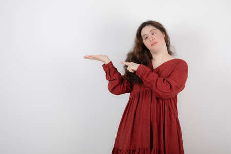 Image of a young cute girl with down syndrome standing and pointing at hand