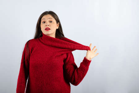 Portrait photo of a young woman model in red warm sweater standing and posingの写真素材
