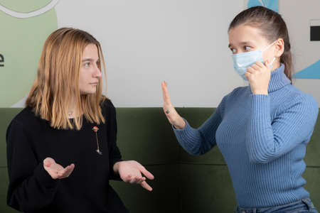 Young blonde girl asking something wrong with her friedn