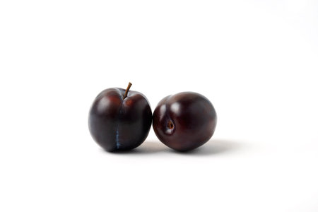 Twin black cherry plums isolated on white backgroundの写真素材