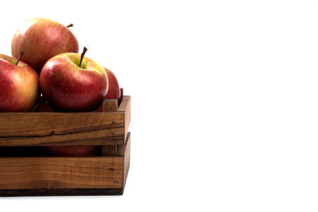 Fresh apples in a wooden crate isolated on white backgroundの写真素材