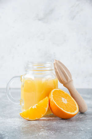 A glass pitcher of juice with fresh orange fruits on stone backgroundの写真素材